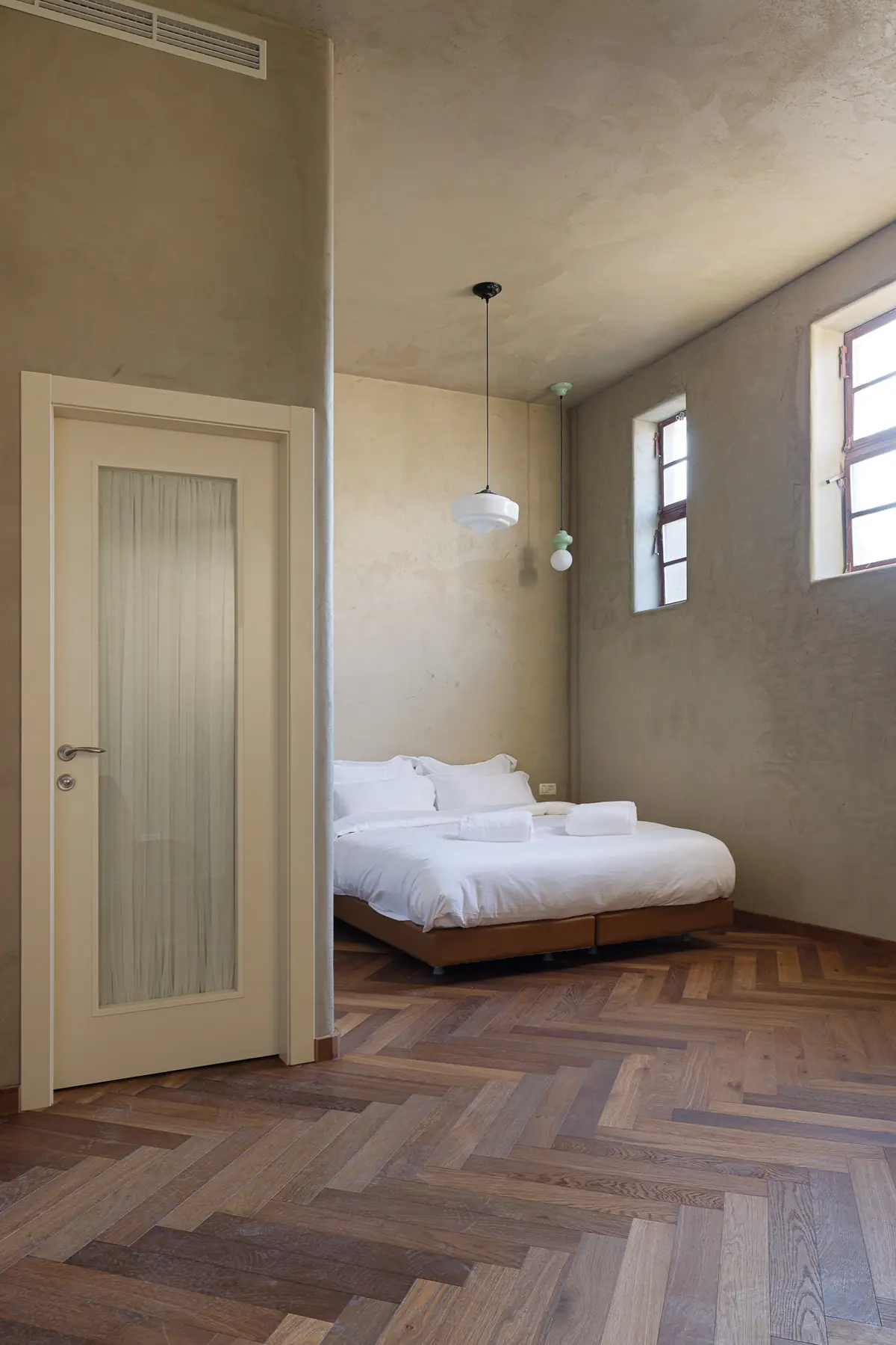 Une chambre, parquet en chevrons et hautes fenêtres